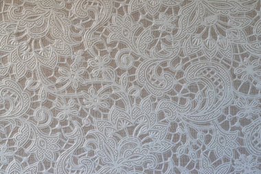 Yumuşak, açık gri arka planda beyaz bir dantel deseni. Dantelin karmaşık tasarımı sofistike ve zarif bir his yaratıyor. Minimalist bir ortamda gösterişli bir doku ve zarafet için mükemmel.. 