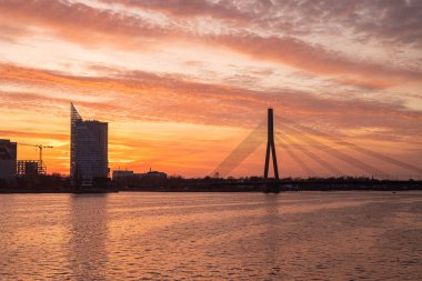 Riga 'daki Vansu Köprüsü üzerinde Akmens Köprüsü' nden çekilen güzel bir günbatımı. Gökyüzü turuncu ve mor tonlarda boyanır, ikonik köprü için çarpıcı bir zemin oluşturur..
