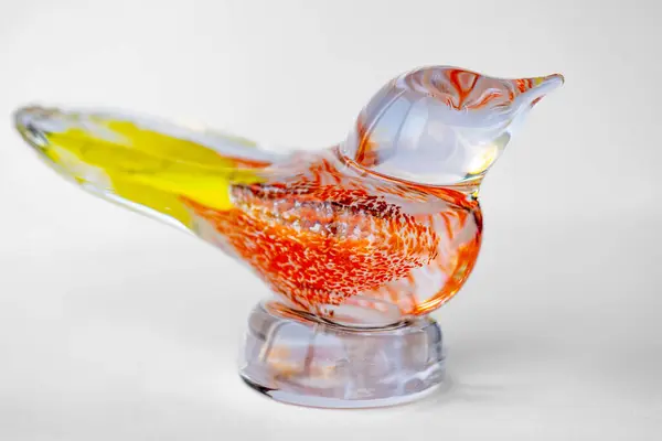 Yumuşak, aydınlık bir arka plana yerleştirilmiş, canlı, renkli benekleri olan, güzel işlenmiş camdan bir kuş.. 