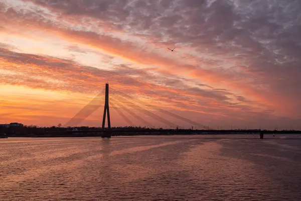 Riga 'daki Vansu Köprüsü üzerinde Akmens Köprüsü' nden çekilen güzel bir günbatımı. Gökyüzü turuncu ve mor tonlarda boyanır, ikonik köprü için çarpıcı bir zemin oluşturur..