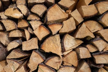 Doğranmış odunların yakın çekim dokusu. Düzenli sıralanmış kütükler doğal ahşap desenleri, ağaç kabuğu dokularını ve dairesel büyüme halkalarını göstererek mevsimsel, enerji veya doğa temalı görseller için kırsal ve organik bir arkaplan oluşturur..