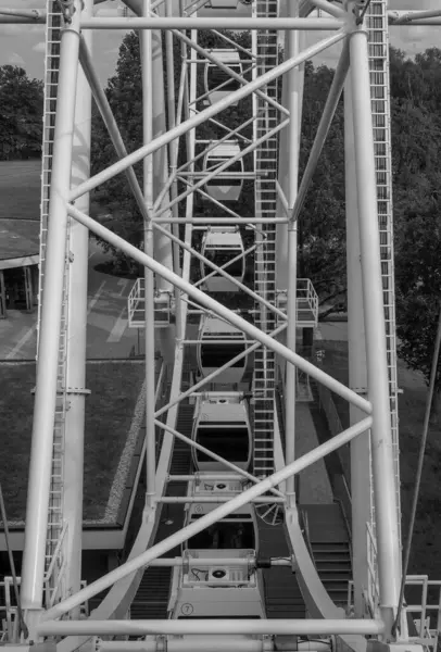Riga, Letonya 'daki dönme dolabın yapısal detaylarını gösteren siyah beyaz bir fotoğraf. Görüntü, gökyüzüne karşı metal iskeletin karmaşık geometrisini ve kontrastını vurgular. 