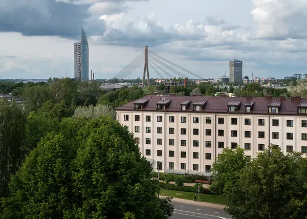 Riga Dönme dolabından çekilen renkli fotoğraf, Vanu Köprüsü 'nün suyun üzerinde uzandığı Daugava Nehri' nin geniş bir görüntüsünü yakalıyor. Günümüz Saules Akmens (Güneş Taşı) binası yakınlarda yer almaktadır..