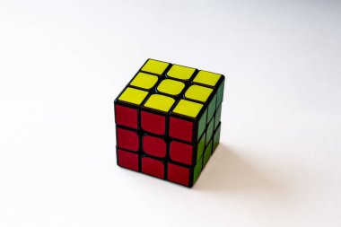 Mükemmel çözülmüş bir Rubik Küpü temiz beyaz bir arkaplana yerleştirilmiş. Küplenmiş, mavi, yeşil, sarı, turuncu ve beyazların canlı renkleri, minimalist ortama keskin bir şekilde karşı, simetri, mantık ve hassasiyeti vurguluyor. 