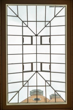 Doğal ışığı filtreleyen dekoratif cam bir çatıya sahip avlunun içindeki binalardan yukarıya doğru bakın. Mimari tasarım zarafet ve modernliği harmanlayarak açık ama korunaklı bir alan yaratır..