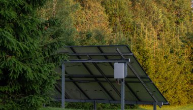 Güneşli bir günde zemine monte edilmiş güneş panellerinin dikiz görüntüsü, kırsal bir ortamda, sürdürülebilir teknolojinin doğal çevreye entegre olduğunu sembolize ederek, panellerin destekleyici yapısını ve hizalanmasını gösteriyor..