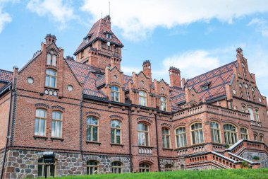 Yaz boyunca açık bir gökyüzü altında yemyeşil ile çevrili Letonya 'daki Jaunmokas Sarayı manzarası.