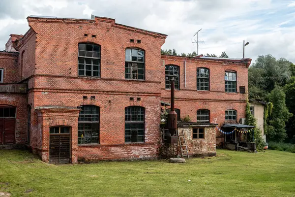 Eski terk edilmiş endüstriyel kırmızı tuğla bina. Tarihi mimari bozulma ve ihmal belirtileri gösteriyor. Zaman ve sanayi mirasını yansıtan dramatik ve atmosferik bir manzara yaratıyor..