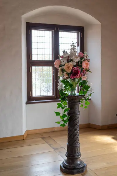 Bir penceresi ve dekoratif duruşu olan tarihi bina. Güzel bir çiçek aranjmanı tutuyor, büyüleyici ve zarif bir atmosfer yaratıyor..