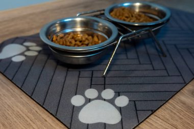 Rubber mat with a paw print design placed on the floor, holding a cat food bowl. Perfect for keeping the feeding area clean and stylish for pets.