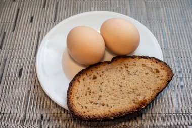 Two eggs on a white plate with a slice of bread on the side  a simple and classic breakfast setup.