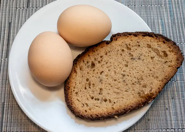 Two eggs on a white plate with a slice of bread on the side  a simple and classic breakfast setup.