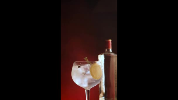 濃い赤い煙草の背景に回転する氷と銀のトニックカップ バーティカルビデオ — ストック動画