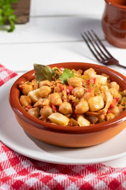 Ev yapımı Ropa vieja, tipik Kanarya usulü nohut güveci, beyaz masadaki toprak kap güveçte. Dikey biçim.