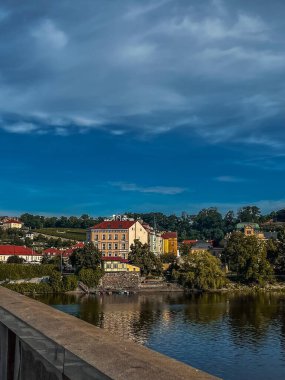 Nehir kıyısında bir şehir. Nehrin üzerinde bir köprü. Sonbahar şehri. Nehrin panoramik manzarası. Tepsiler taş duvarın yanında. Bulutlu. Prag 'daki Vltava Nehri ve Charles Köprüsü