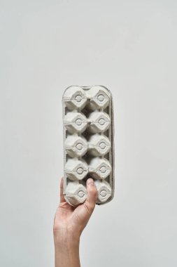 Partial male hand holding cardboard egg tray. Ecology safety and protection. Waste disposal and recycling. Environmental sustainability. Isolated on white background. Studio shoot. Copy space