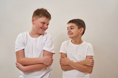 Kollarını kavuşturup birbirlerine bakan, gülümseyen beyaz çocuklar. Zoomer kuşağının arkadaşları. Modern gençlik yaşam tarzı kavramı. Arkadaşlık. Beyaz arka planda izole edilmiş. Stüdyo çekimi. Boşluğu kopyala