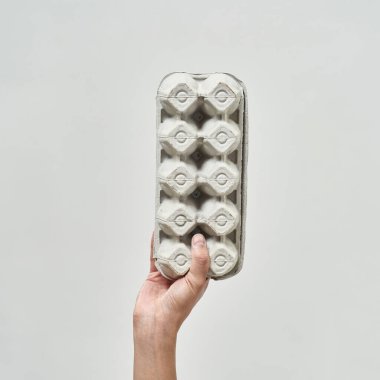 Kırpılmış erkek eli karton yumurta tepsisi tutuyor. Ekoloji güvenliği ve korunma. Çöp öğütücü ve geri dönüşüm. Çevresel sürdürülebilirlik. Beyaz arka planda izole edilmiş. Stüdyo çekimi. Boşluğu kopyala