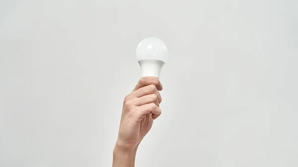 Cropped male hand holding lightbulb. Energy saving. Ecology safety and protection. Waste disposal and recycling. Environmental sustainability. Isolated on white background. Studio shoot. Copy space