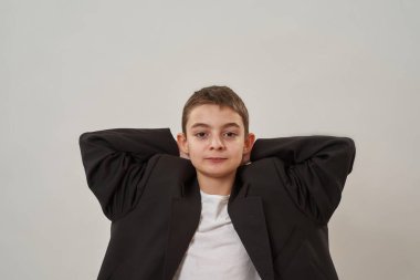 Kısmen yakışıklı, ciddi, beyaz bir çocuk kameraya bakıyor. Zoomer neslinin erkek çocuğu iş ceketi giyiyor. Erkek güzelliği kavramı. Beyaz arka planda izole edilmiş. Stüdyo çekimi. Boşluğu kopyala