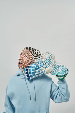 Kafasında plastik çöp torbası olan Asyalı gergin bir adam. Ekoloji güvenliği ve korunma. Çöp öğütücü ve geri dönüşüm. Çevresel sürdürülebilirlik. Beyaz arka plan. Stüdyo çekimi. Boşluğu kopyala