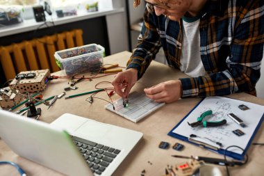 Elektronik ekipmanlara kablo ve kablo bağlayan kesik erkek teknisyen. Gözlüklü kızıl saçlı adam ofiste bilimsel deneyler yapıyor. Modern teknoloji ve yenilik