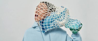 Kafasında plastik çöp torbası örülmüş Asyalı gergin bir adam. Ekoloji güvenliği ve korunma. Çöp öğütücü ve geri dönüşüm. Çevresel sürdürülebilirlik. Beyaz arka plan. Stüdyo çekimi. Boşluğu kopyala