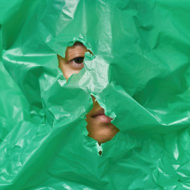 İnsan ağzı ve gözü kameraya plastik torba arkasından bakıyor. Ekolojik güvenlik ve koruma kavramı. Çöp öğütücü ve geri dönüşüm. Çevresel sürdürülebilirlik fikri