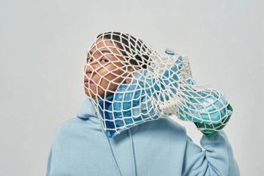 Kafasında plastik çöplerle dolu bir çanta taşıyan Asyalı adam. Ekoloji güvenliği ve korunma. Çöp öğütücü ve geri dönüşüm. Çevresel sürdürülebilirlik. Beyaz arka plan. Stüdyo çekimi. Boşluğu kopyala