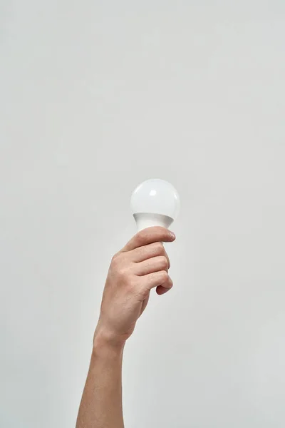 Partial male hand holding lightbulb. Energy saving. Ecology safety and protection. Waste disposal and recycling. Environmental sustainability. Isolated on white background. Studio shoot. Copy space