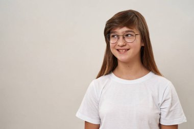 Partial view of smiling caucasian teenage girl looking away. Female child of zoomer generation wearing glasses. Modern youngster lifestyle. Isolated on white background. Studio shoot. Copy space