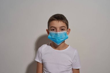 Caucasian little boy wearing medical mask looking at camera. Male child of zoomer generation. Health protection during Coronavirus pandemic. Isolated on white background. Studio shoot. Copy space