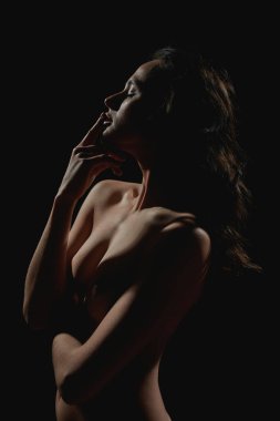 Yandan bakınca dudaklarına dokunan çıplak Avrupalı seksi bir kız görüyorum. Kadın güzelliği. Tutku ve arzu. Güzel, sıska, esmer kadın. Karanlık arka planda izole edilmiş. Stüdyo çekimi
