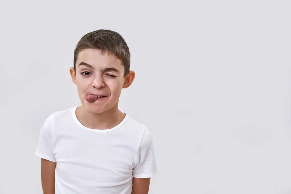 Băieţelul Caucazian Face Ochiul Îşi Scoate Limba Uită Cameră Copil Fotografie de stoc