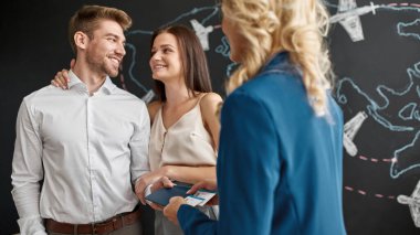 Cropped female tourist agent giving international passports with air tickets to smiling caucasian couple in travel agency. Client service. Vacation, tourism, weekend and journey. Trip booking