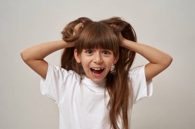 Kafkasyalı korkmuş küçük kız başını tutuyor ve kameraya bakıyor. Zoomer kuşağının dişi çocuğu. Modern gençlik yaşam tarzı kavramı. Beyaz arka planda izole edilmiş. Stüdyo çekimi