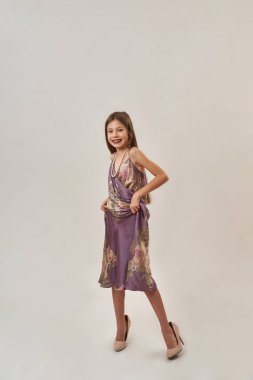 Zoomer kuşağından güzel, güler yüzlü beyaz bir kız. Elbise ve kolye takıp kameraya bakıyor. Kadın güzelliği. Beyaz arka planda izole edilmiş. Stüdyo çekimi. Boşluğu kopyala