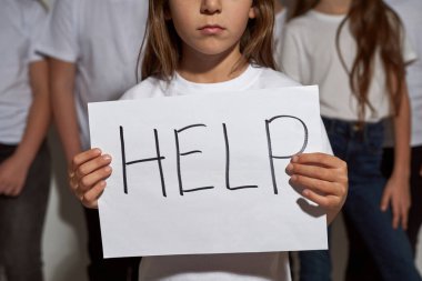 Kâğıt levha tutan küçük kızın belirsiz yüzü. Zoomer kuşağının kısmi çocuklarının geçmişiyle ilgili yardım sözcüğü. Gençlik mitingi ve gösteri. Stüdyoda beyaz arka planda izole edilmiş.