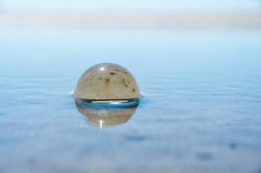 Mavi özgürlük kavramı: Kristal Top suyu ve gökyüzünü maviyle yansıtıyor. Kumun üzerinde güzel, yaratıcı manzara fotoğrafçılığı.