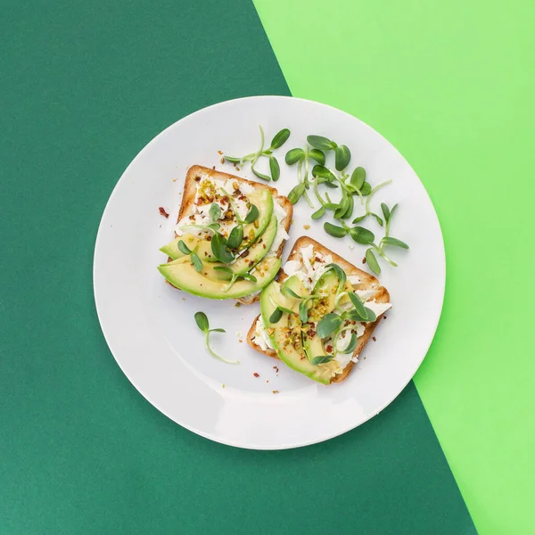 美味而健康的三明治 夹杂着奶油鳄梨 煮熟的鸡蛋和白盘上新鲜的微绿色 顶部视图 — 图库照片