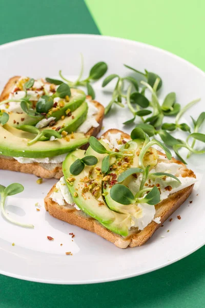 美味健康的三明治 夹杂着奶油鳄梨 煮熟的鸡蛋和白盘上新鲜的微绿色 — 图库照片