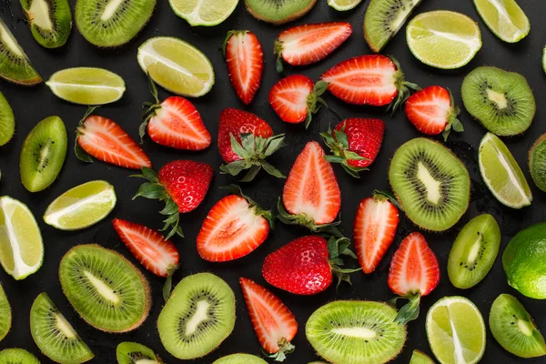 Mieszanina Dojrzałych Owoców Plasterkach Kiwi Truskawek Limonki Czarnym Tle — Zdjęcie stockowe