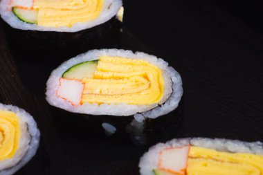 Çırpılmış yumurtadan yapılan suşi Japon salatalığı ve yengeç çubukları yosunlara sarılır ve kolay yemek için parçalara ayrılır..