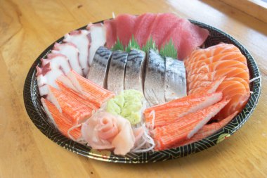 Japon desenli tepside çeşit çeşit saşimi. Taze ton balığı, taze somon, taco dokunaçları, yengeç çubukları ve uskumru, wasabi ve zencefil turşusuyla süslenmiş..