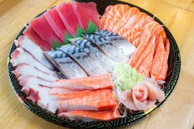 Japon desenli tepside çeşit çeşit saşimi. Taze ton balığı, taze somon, taco dokunaçları, yengeç çubukları ve uskumru, wasabi ve zencefil turşusuyla süslenmiş..