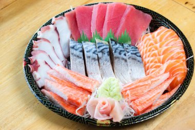 Japon desenli tepside çeşit çeşit saşimi. Taze ton balığı, taze somon, taco dokunaçları, yengeç çubukları ve uskumru, wasabi ve zencefil turşusuyla süslenmiş..