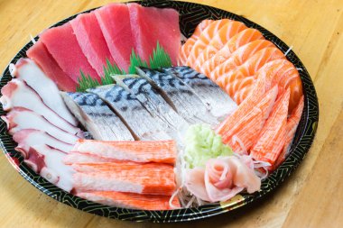 Japon desenli tepside çeşit çeşit saşimi. Taze ton balığı, taze somon, taco dokunaçları, yengeç çubukları ve uskumru, wasabi ve zencefil turşusuyla süslenmiş..