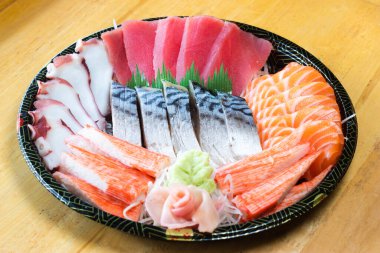 Japon desenli tepside çeşit çeşit saşimi. Taze ton balığı, taze somon, taco dokunaçları, yengeç çubukları ve uskumru, wasabi ve zencefil turşusuyla süslenmiş..