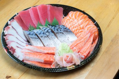 Japon desenli tepside çeşit çeşit saşimi. Taze ton balığı, taze somon, taco dokunaçları, yengeç çubukları ve uskumru, wasabi ve zencefil turşusuyla süslenmiş..