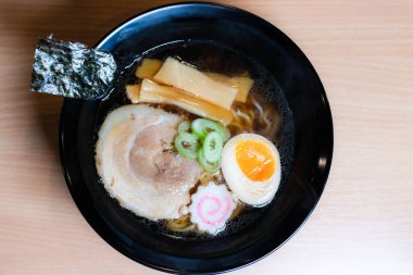 Siyah bardakta soya soslu ramen sosu, üzerine chashu domuz eti, Naruto balık köftesi, soya soslu yumurta turşusu, menma bambu filizleri ve yosun. Ramen kendine özgü bir Japon usulü şehriye çorbası..